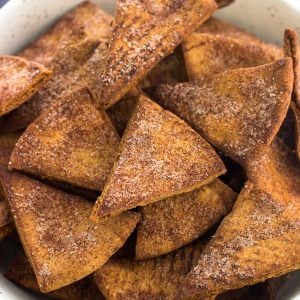 Cinnamon sugar pita chips in a ceramic bowl next to a dish towel