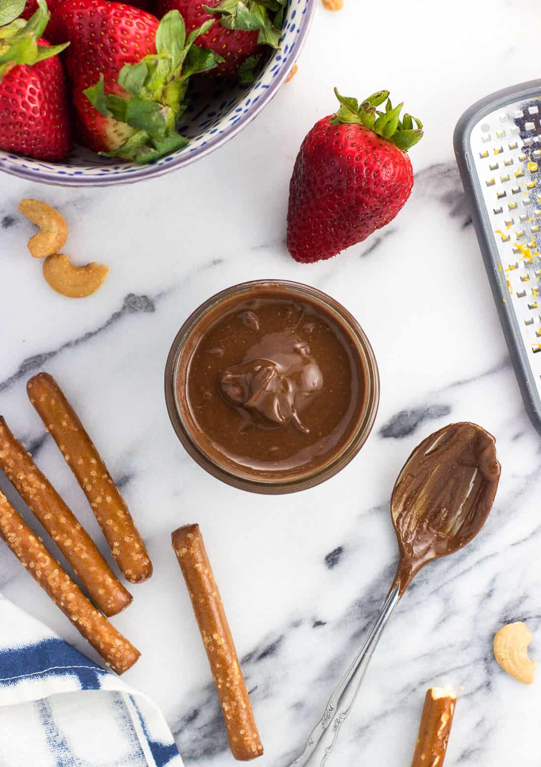 An overhead shot of strawberries, pretzels, cashews, and the cashew butter 