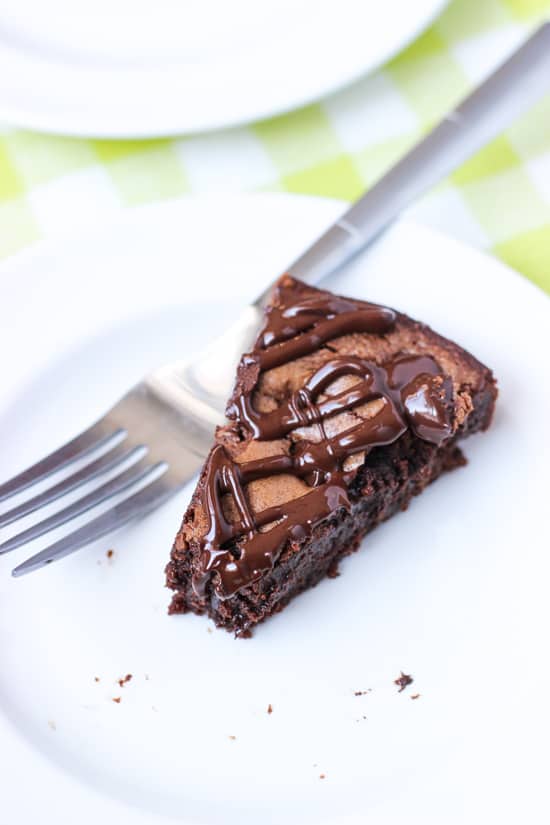 A slice of brownie cake on a dessert plate with a fork.