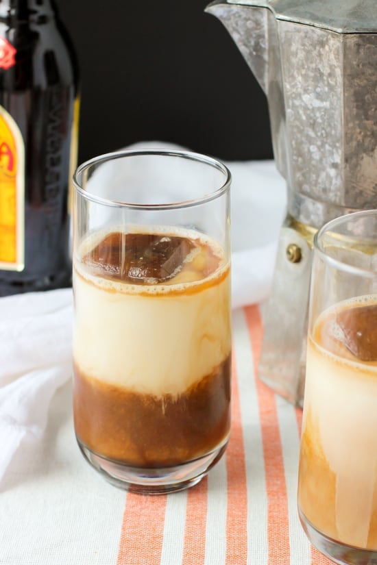 Chai tea concentrate and milk in a glass with a large ice cube.