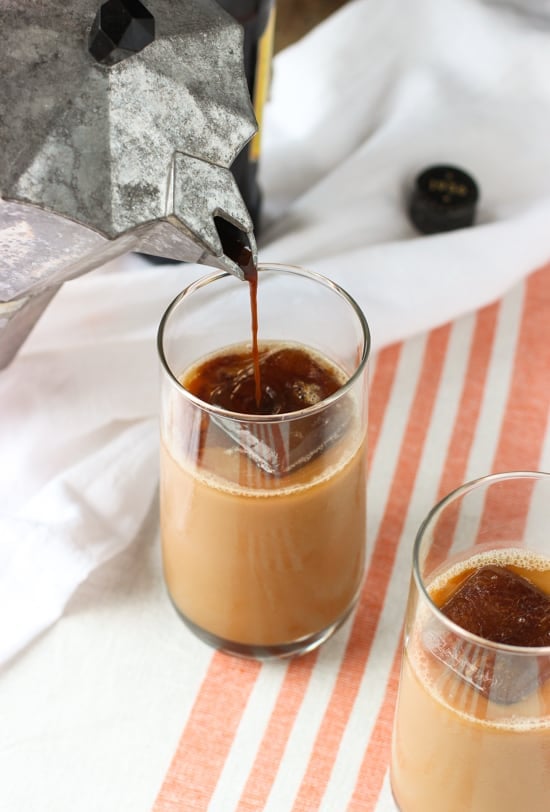 Espresso being poured into a glass of an iced chai latte.