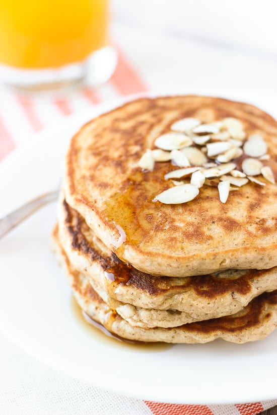 A stack of pancakes on a plate drizzled with maple syrup.