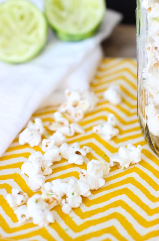 A close-up of popped popcorn kernels on a dishtowel flecked with lime zest