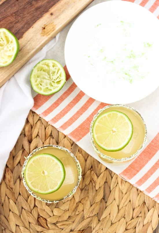 An overhead shot of two beergaritas in rocks glasses next to squeezed lime halves and a plate where the rims were salted