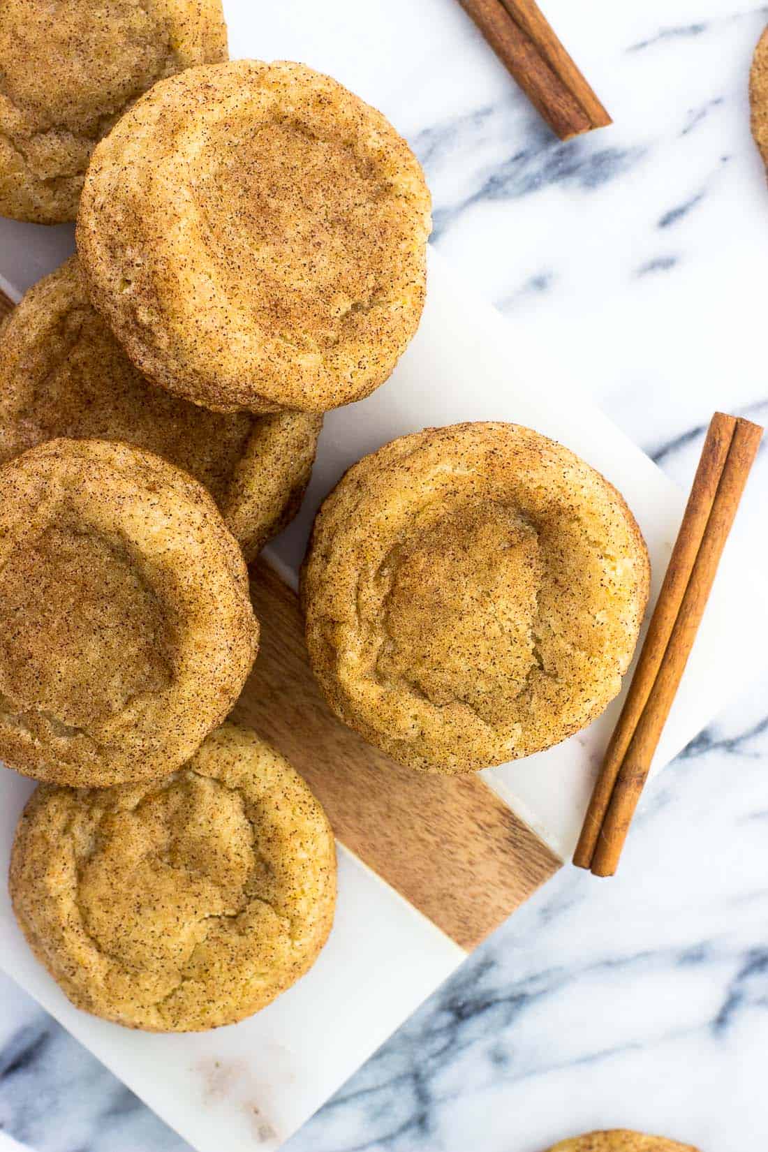 Snickerdoodle cookies on a serving tray next to whole cinnamon sticks