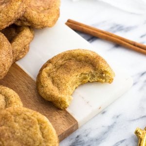 An orange ginger snickerdoodle cookie on a marble serving tray with a bite taken out of it