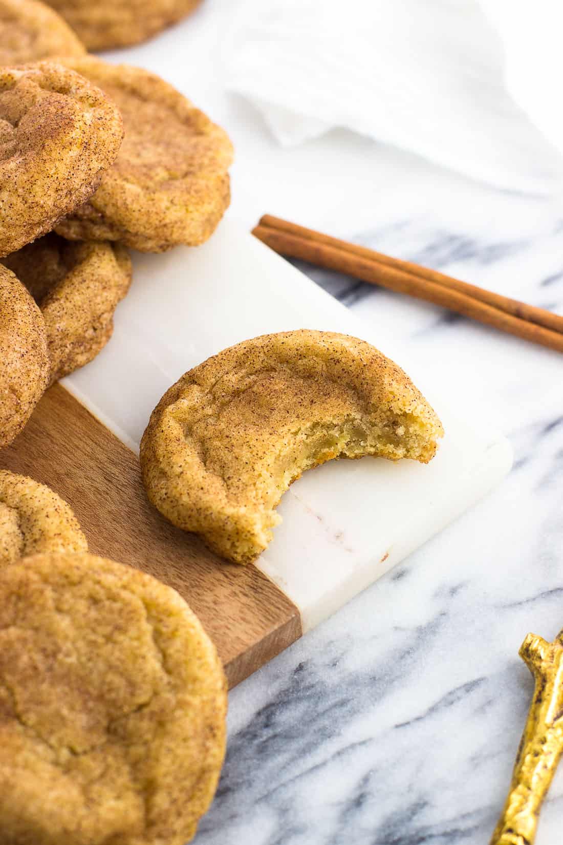 A snickerdoodle cookie on a marble serving tray with a bite taken out of it