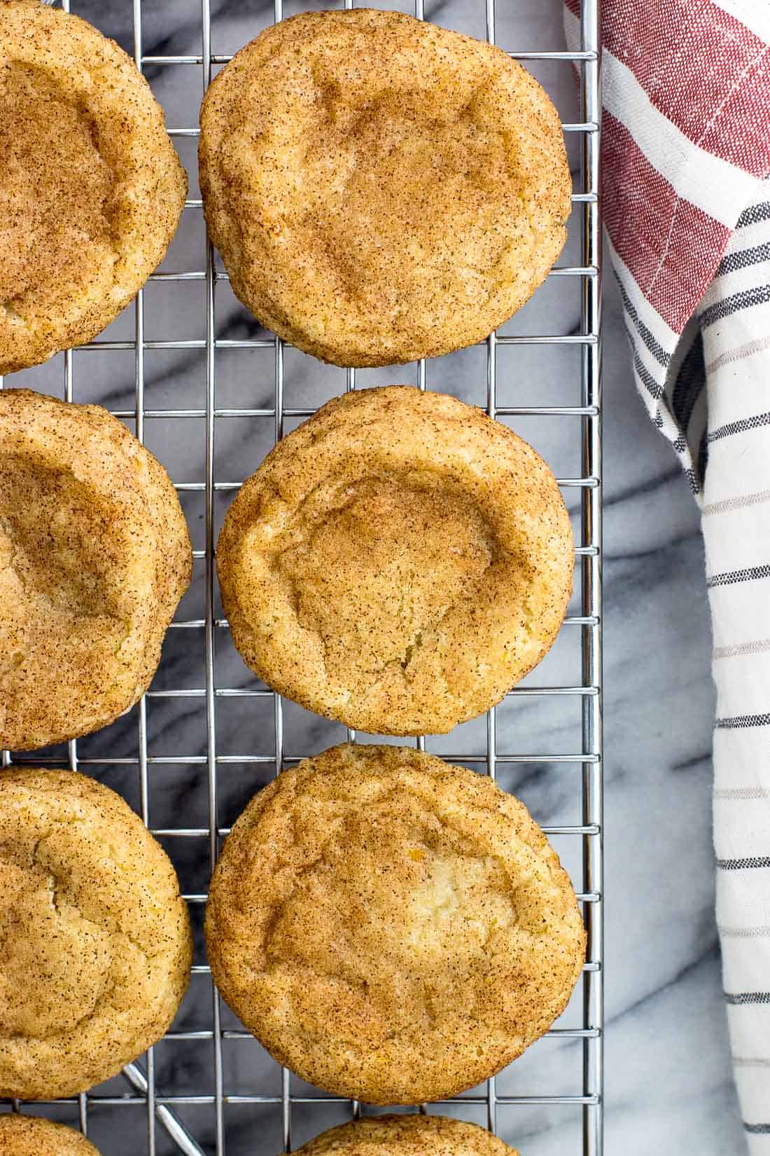 Snickerdoodles cooling on a metal wire rack next to a linen napkin