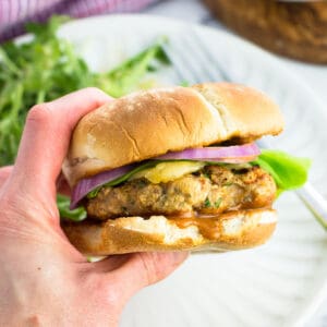 A hand holding a chicken burger.