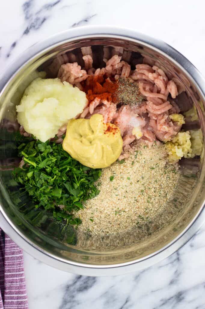 Chicken burger ingredients in a metal bowl before mixing.