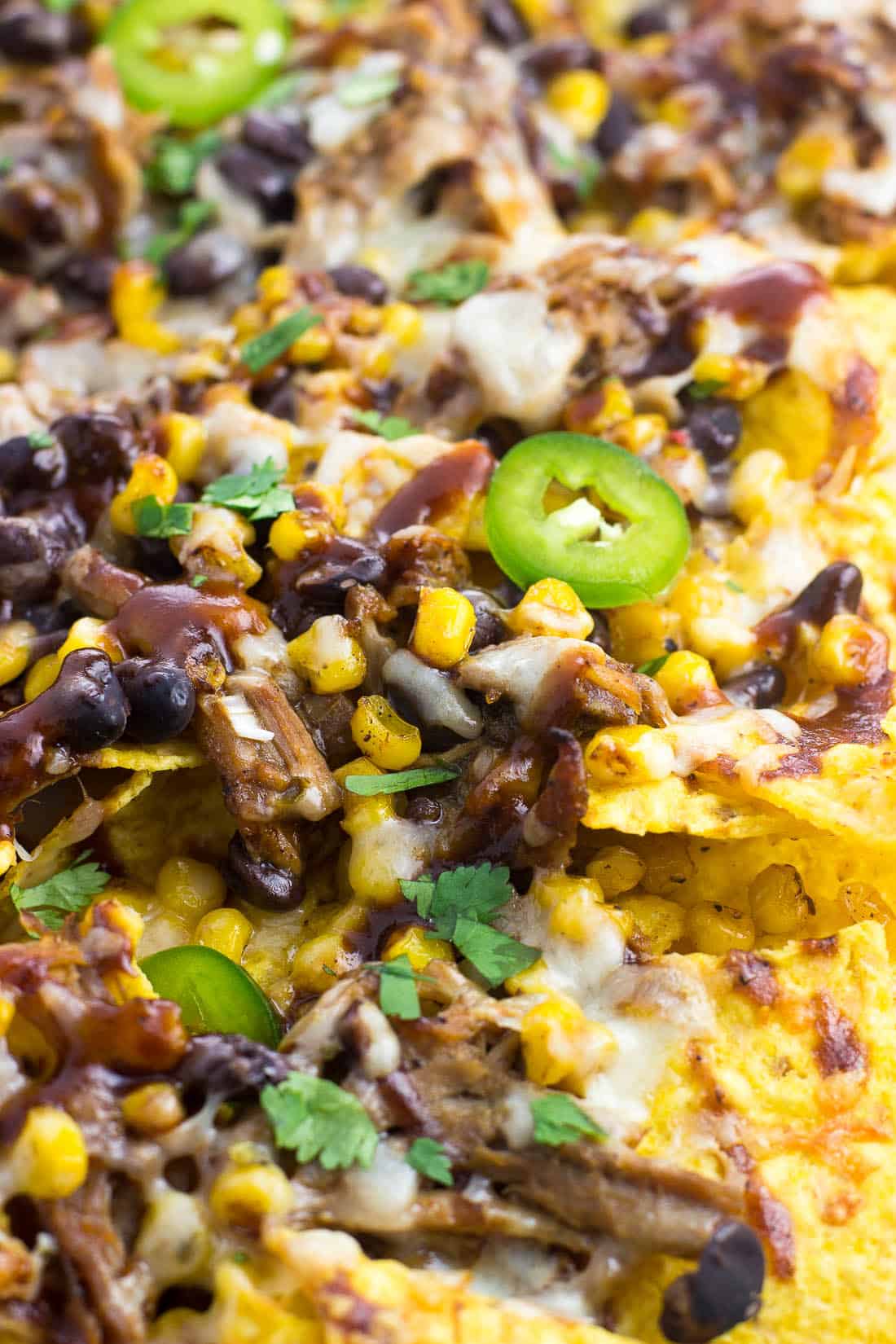 A close-up picture of pulled pork nachos on a sheet pan.