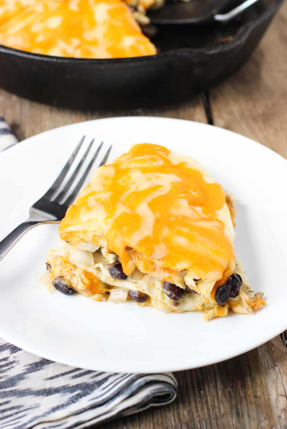 A segment of tortilla pie on a plate with a fork.