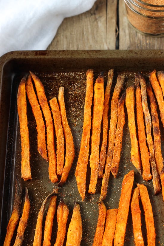 Baked sweet potato fries lined up on a metal sheet pan.