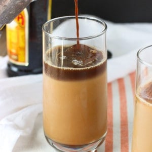A layer of espresso poured on top of the iced chai latte in a glass.