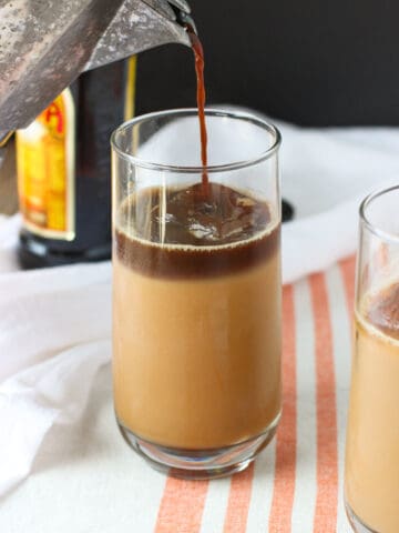 A layer of espresso poured on top of the iced chai latte in a glass.