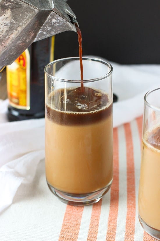 A layer of espresso poured on top of the iced chai latte in a glass.