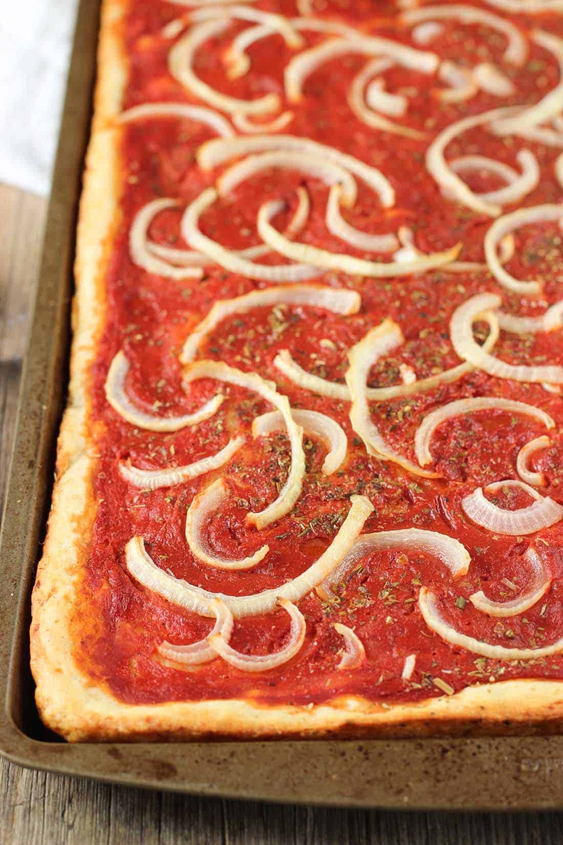 A tray of focaccia pizza unsliced on a baking sheet.