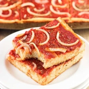 Two slices of focaccia pizza stacked on top of one another on a plate.