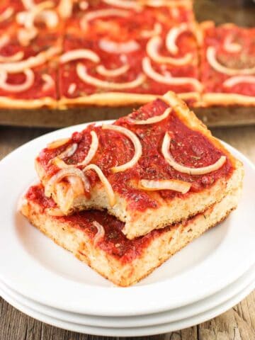 Two slices of focaccia pizza stacked on top of one another on a plate.