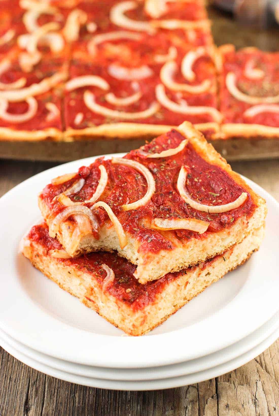 Two slices of focaccia pizza stacked on top of one another on a plate.