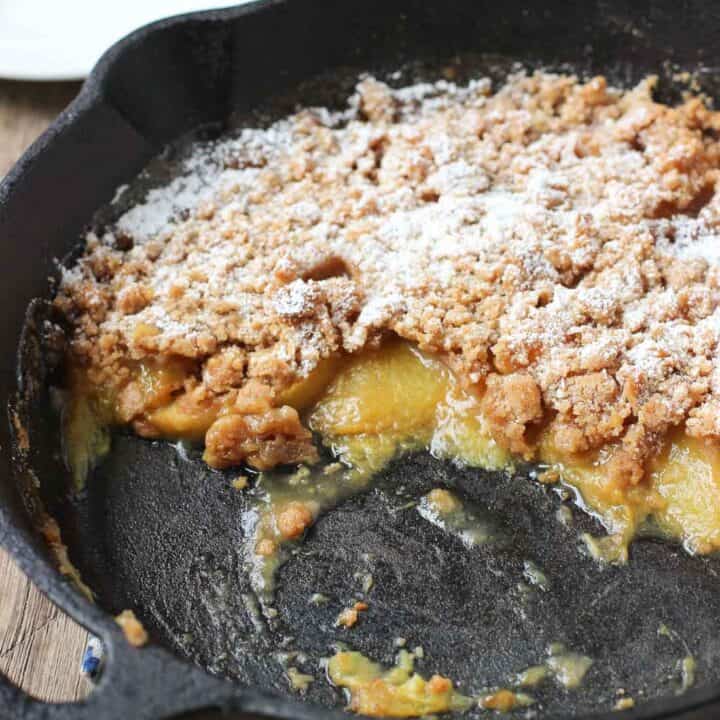 A side-section view of the fruit crisp in its cast iron pan after half has been removed
