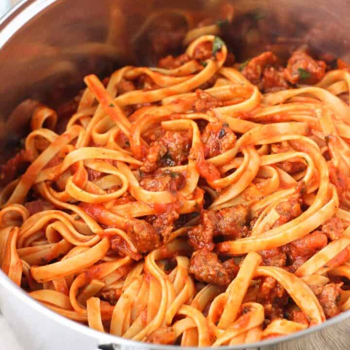 A large pot filled with sausage fettuccine.