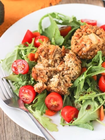 Tuna cakes on a garden salad on a plate.