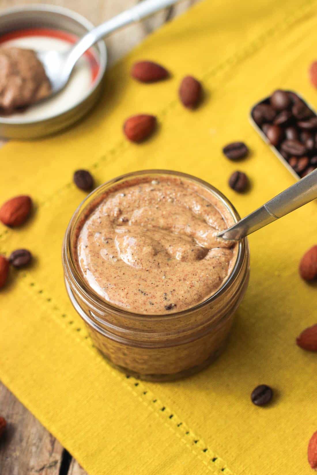 A small glass jar on a linen napkin filled with almond butter 