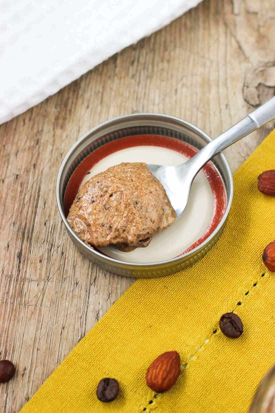 A spoonful of almond butter resting on the lid of the glass jar