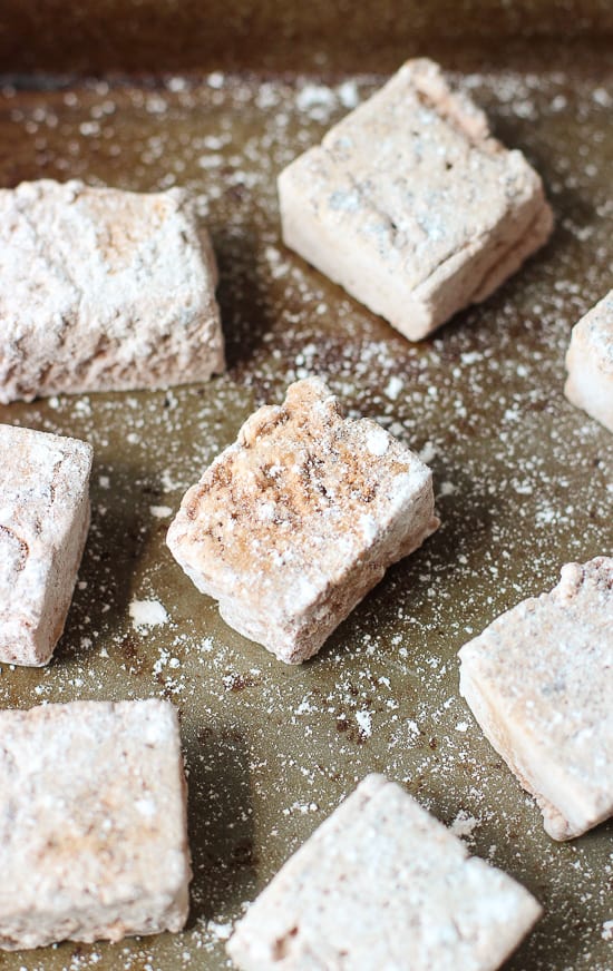 A close-up of a powdered sugar dusted marshmallow on a baking sheet.