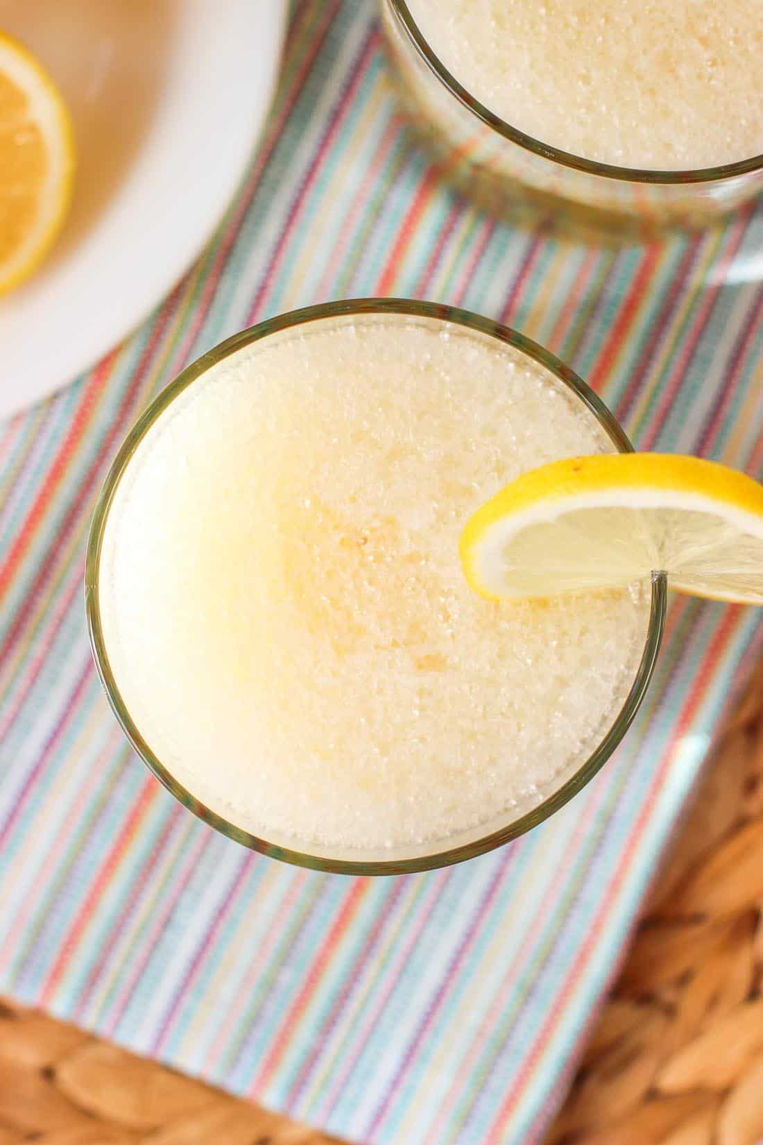 An overhead shot of the fine crushed ice layer of the cocktail with a lemon round balancing on the rim of the glass