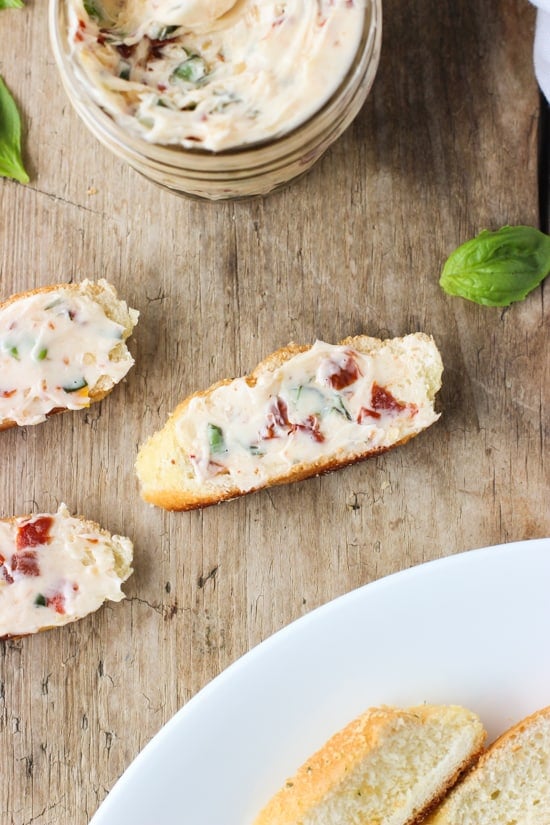 An overhead picture of the butter spread on crostini with a small glass jar of the softened butter in the background