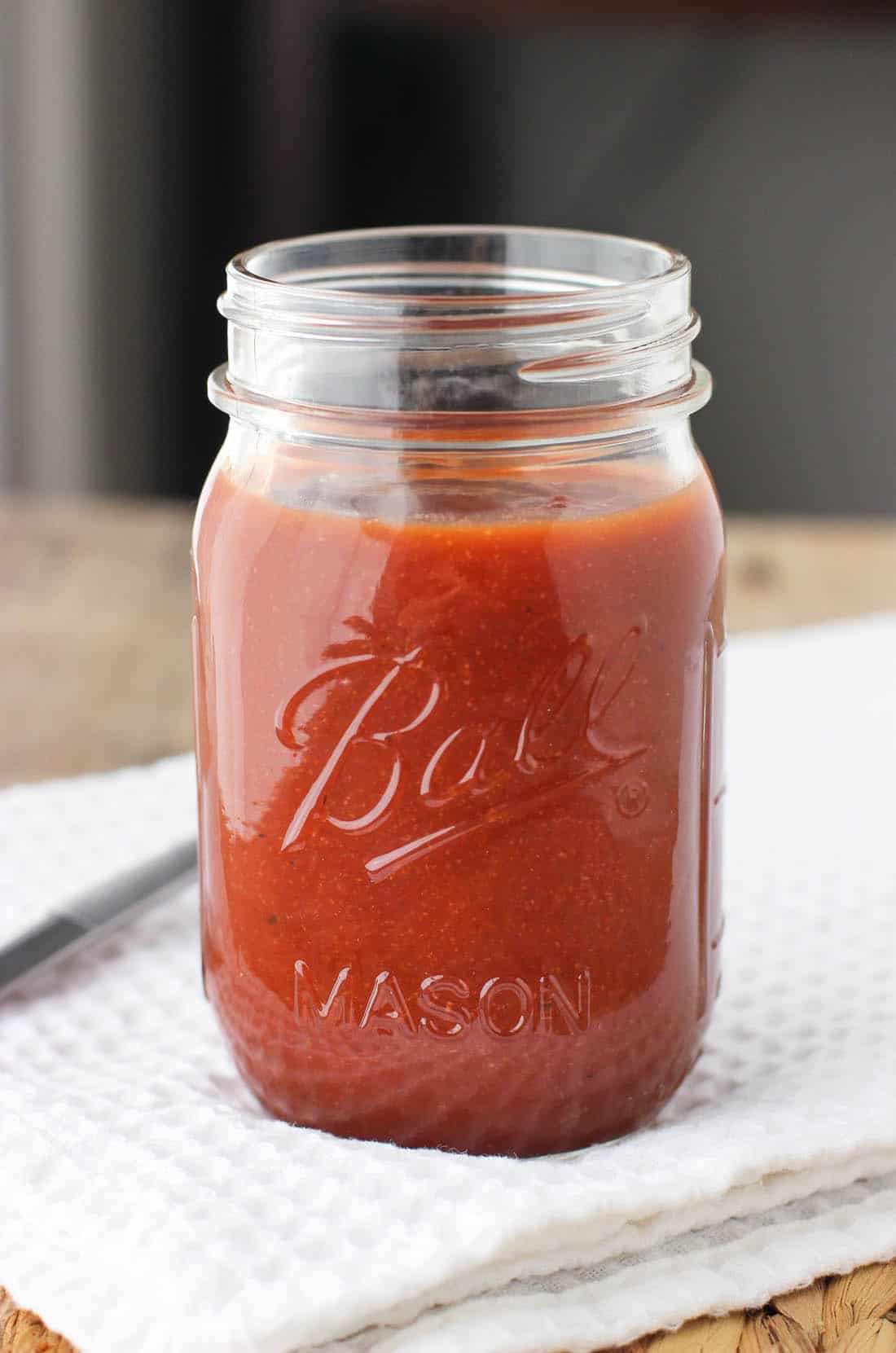 A large glass jar filled with maple bourbon BBQ sauce.