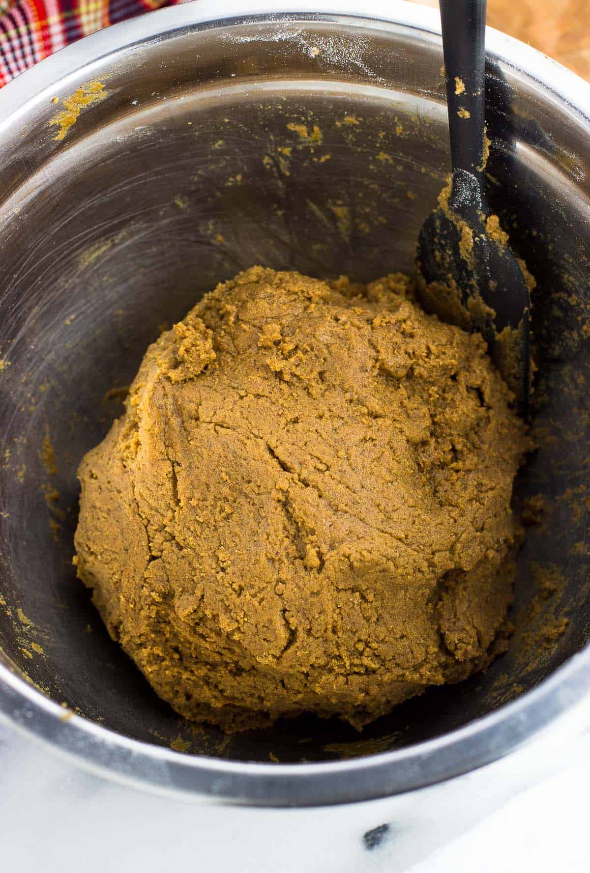 Cookie dough in a metal mixing bowl with a spatula.