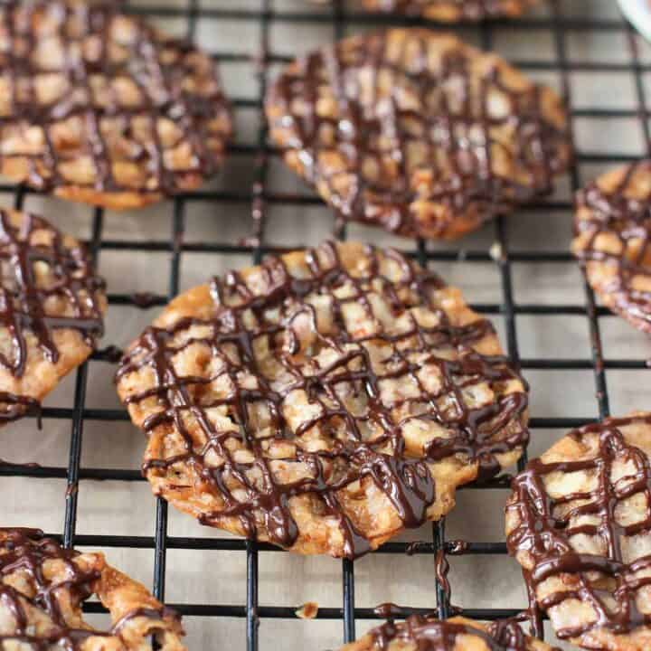 Melted chocolate drizzled on florentines on a wire rack.