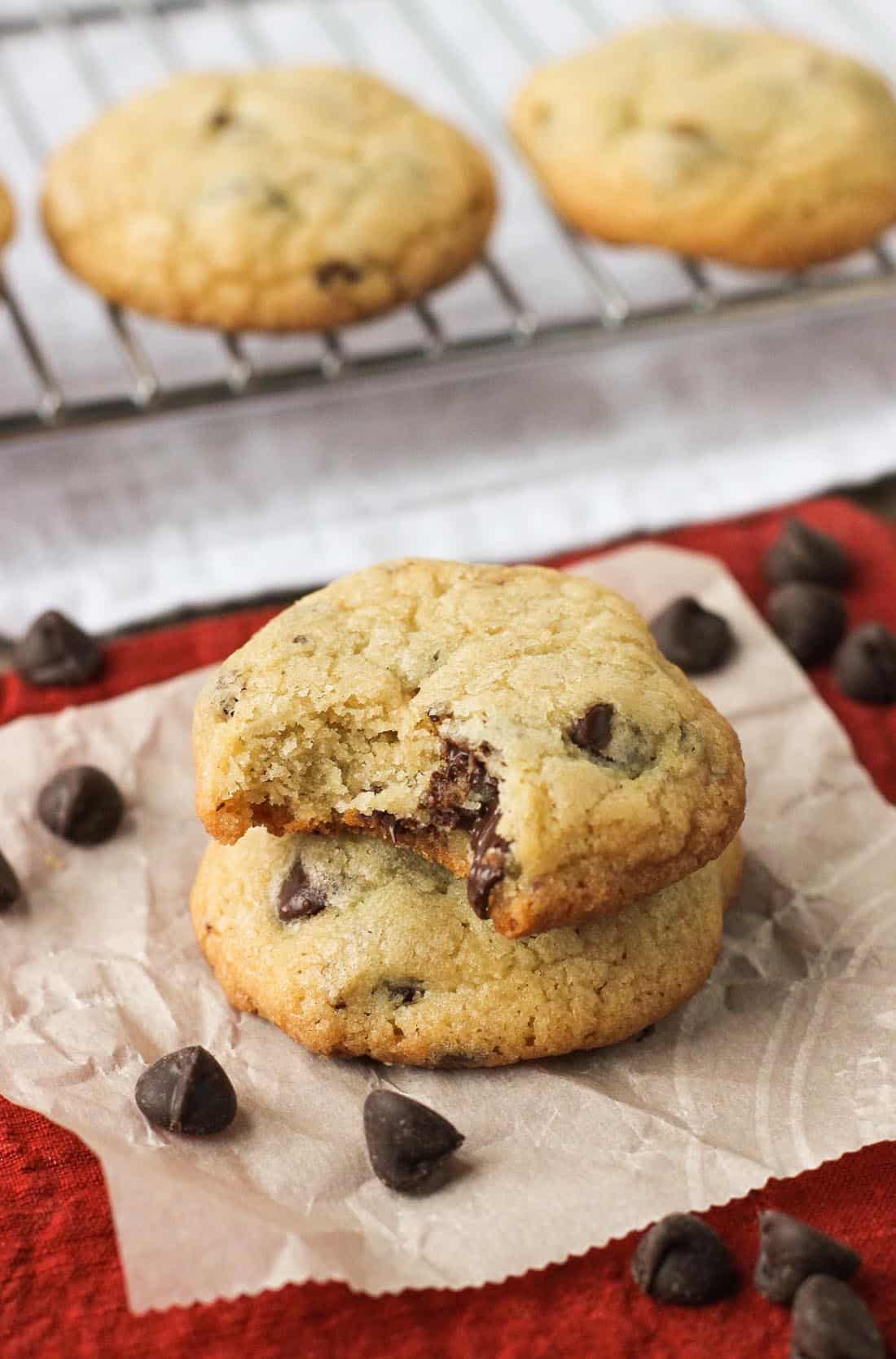 Two chocolate chip cookies stacked on top of one another with a bite taken out of the top one.