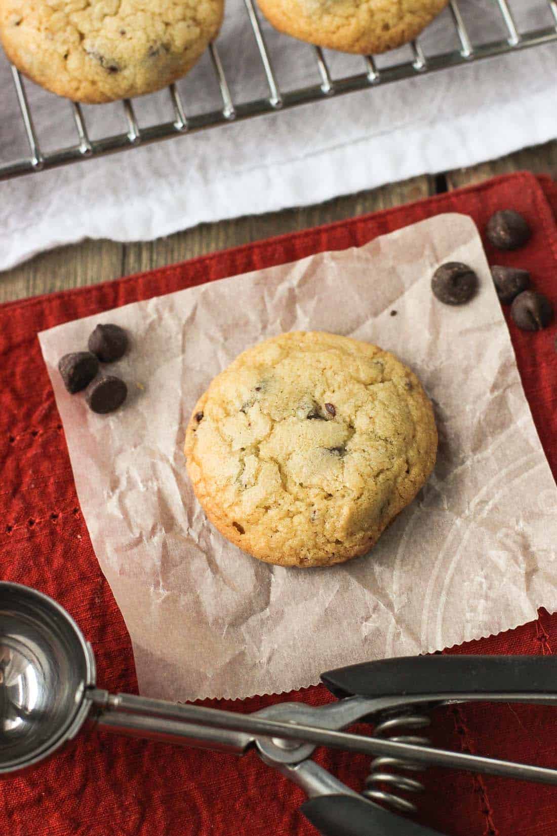 A chocolate chip cookie on a sheet of parchment paper.