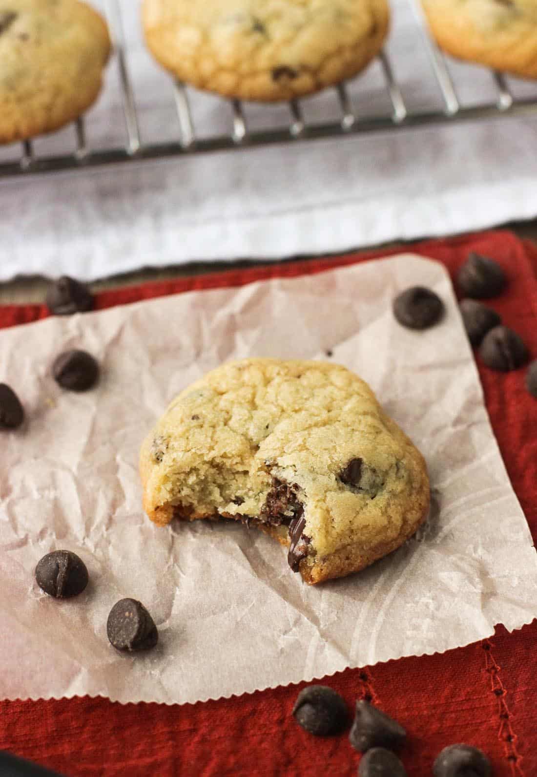 A cookie on a sheet of parchment paper with a bite taken out of it.