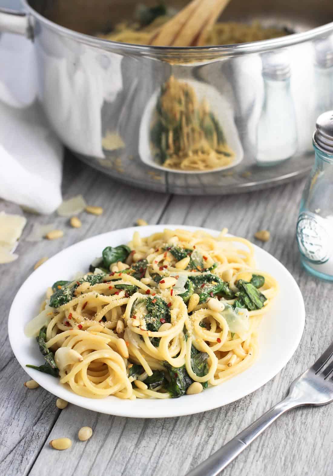 A plate of pasta in front of the large metal pasta pot.