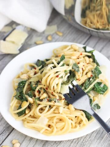 A fork twirled into a serving of pasta on a plate.