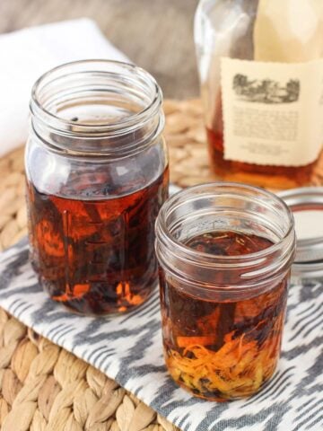 Two jars of vanilla extract: one with vanilla beans and one also with orange rind.