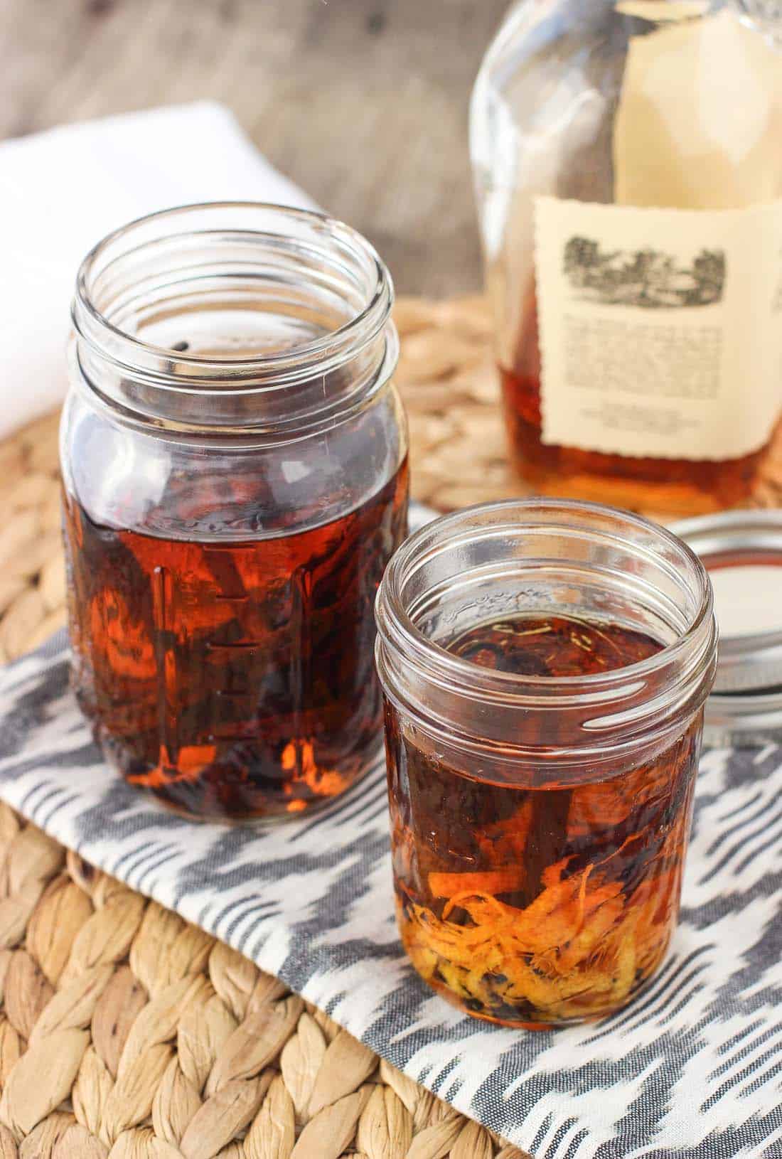 Two jars of vanilla extract: one with vanilla beans and one also with orange rind.