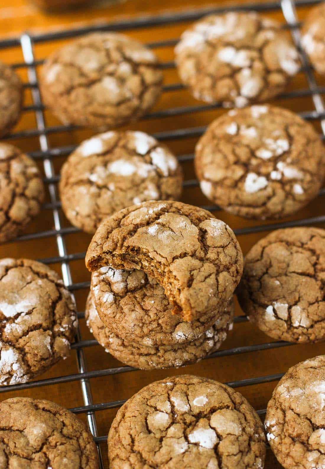 Cookies cooling on a wire rack, with a stack of cookies in the front with a big bite taken out of the top cookie.