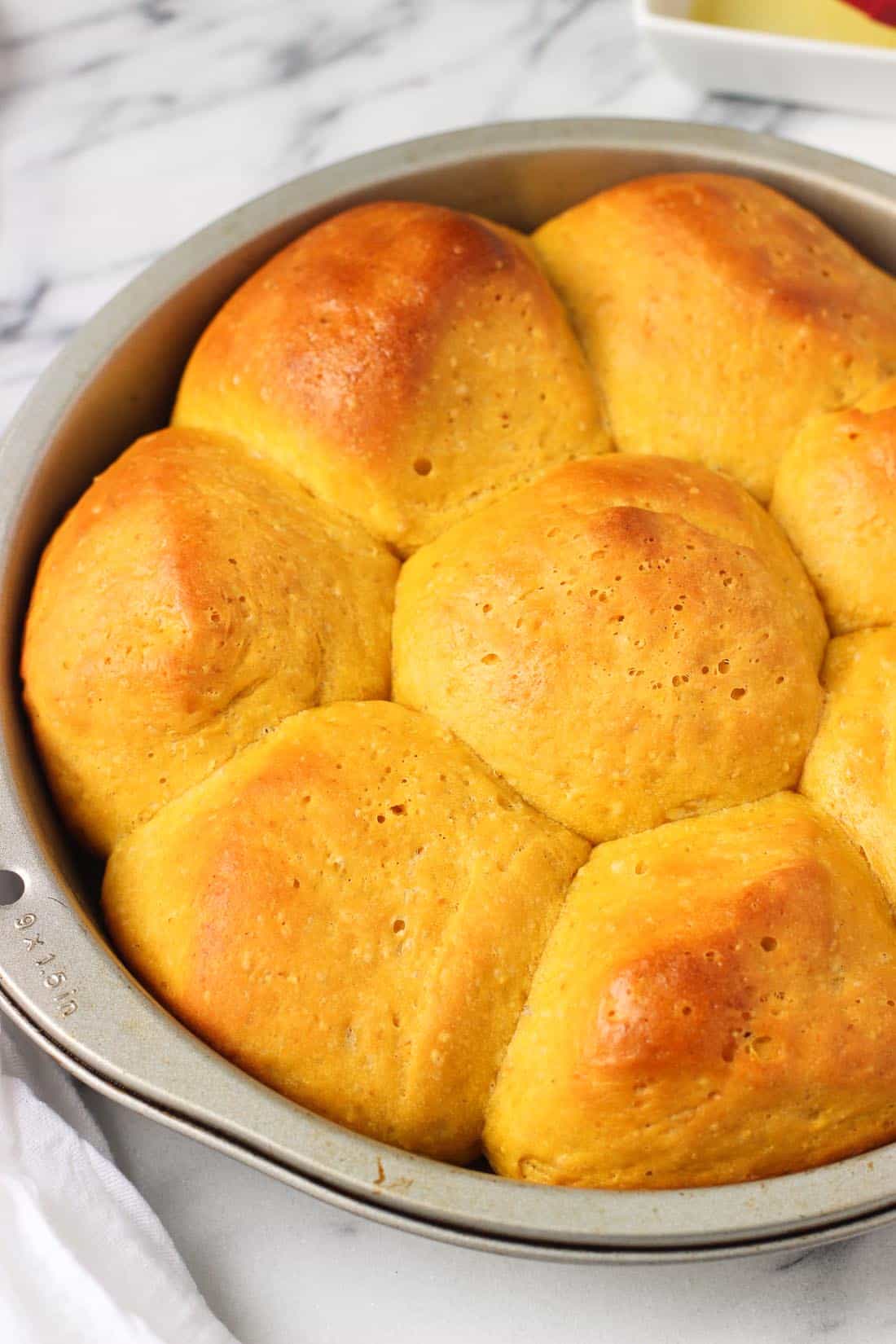 Pumpkin rolls baked next to one another in a round metal pan.