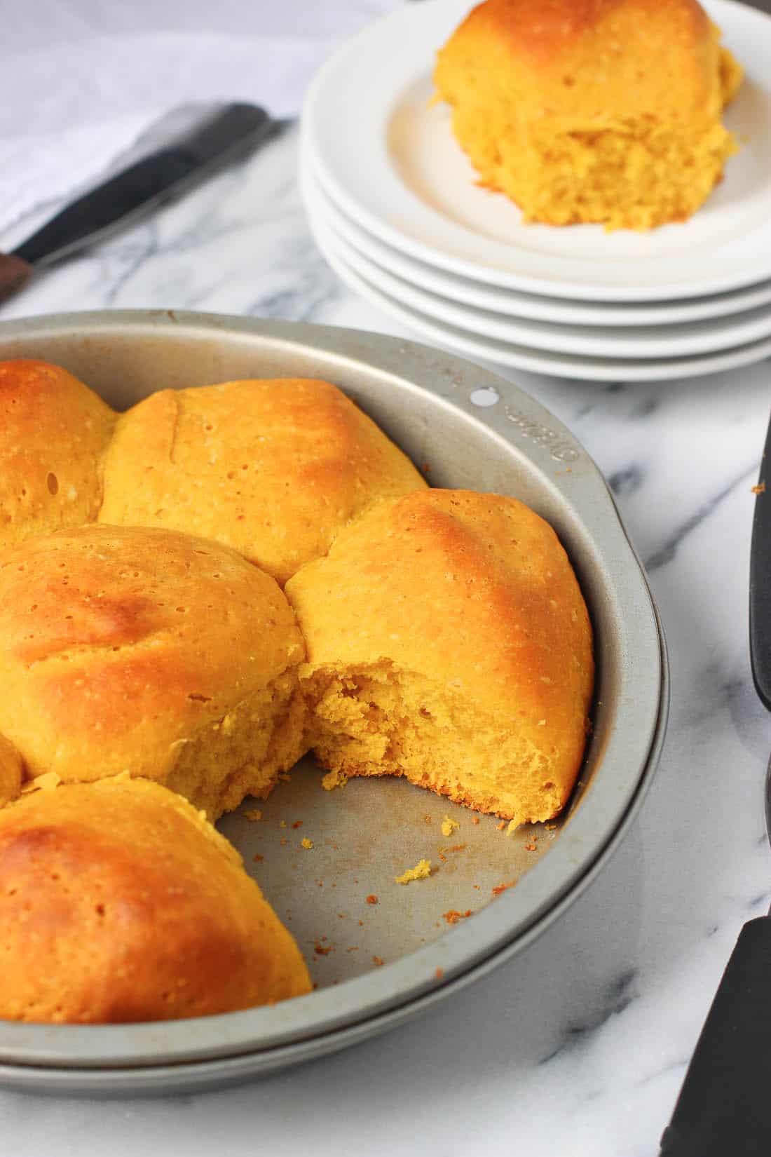 One baked roll removed to a plate from the pan.