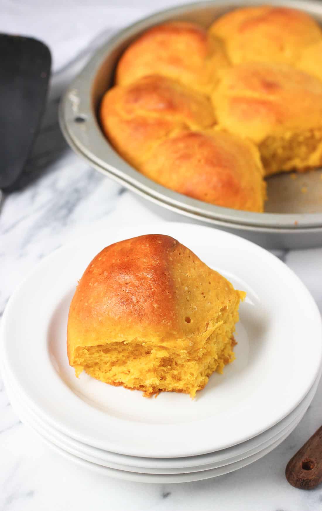 A roll pulled apart from the rest in the pan and put on a plate.