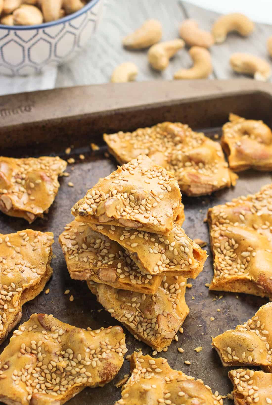 A stack of sesame cashew brittle on a metal baking sheet.