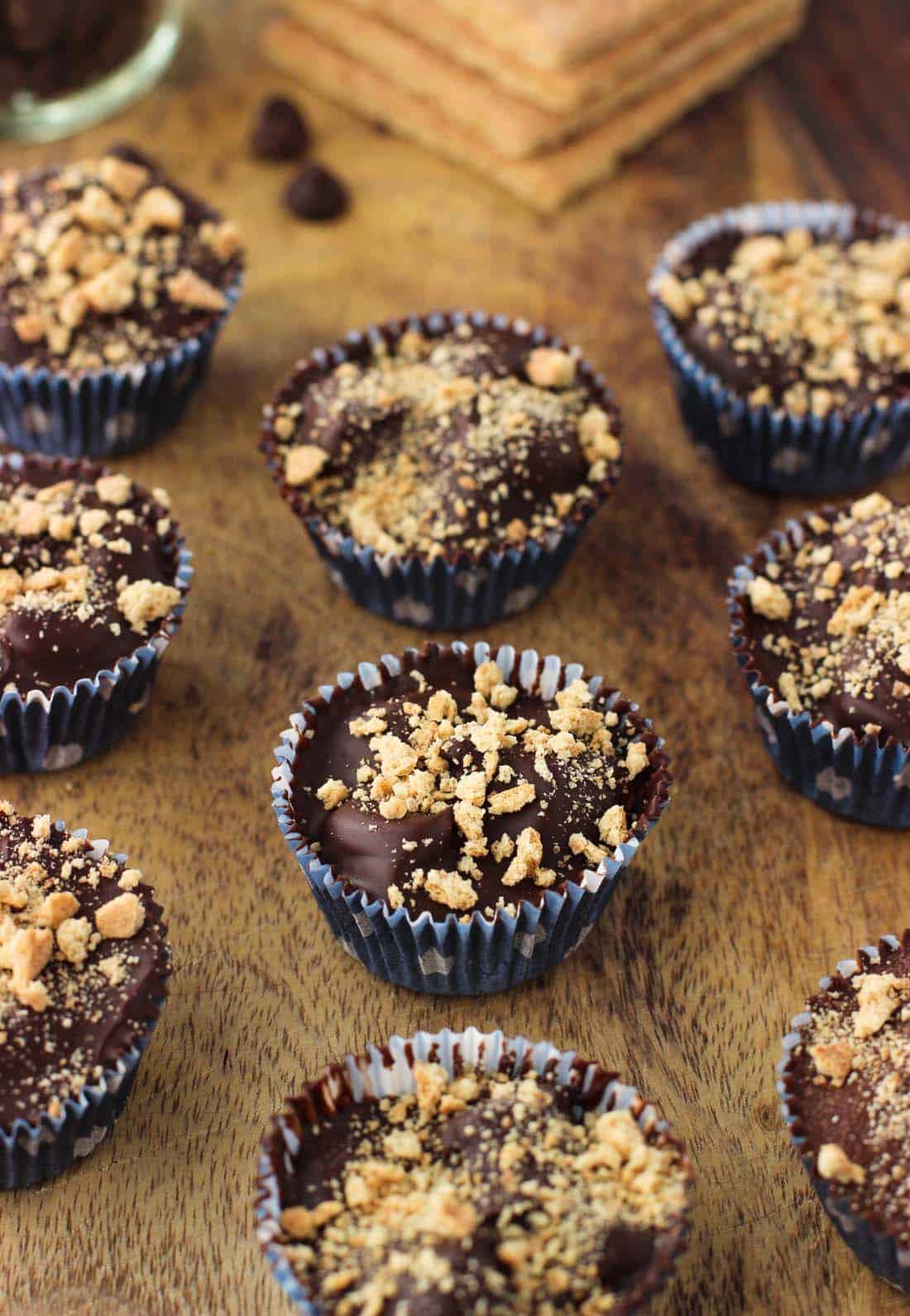 Mini s\'mores cups lined up on a wooden board.