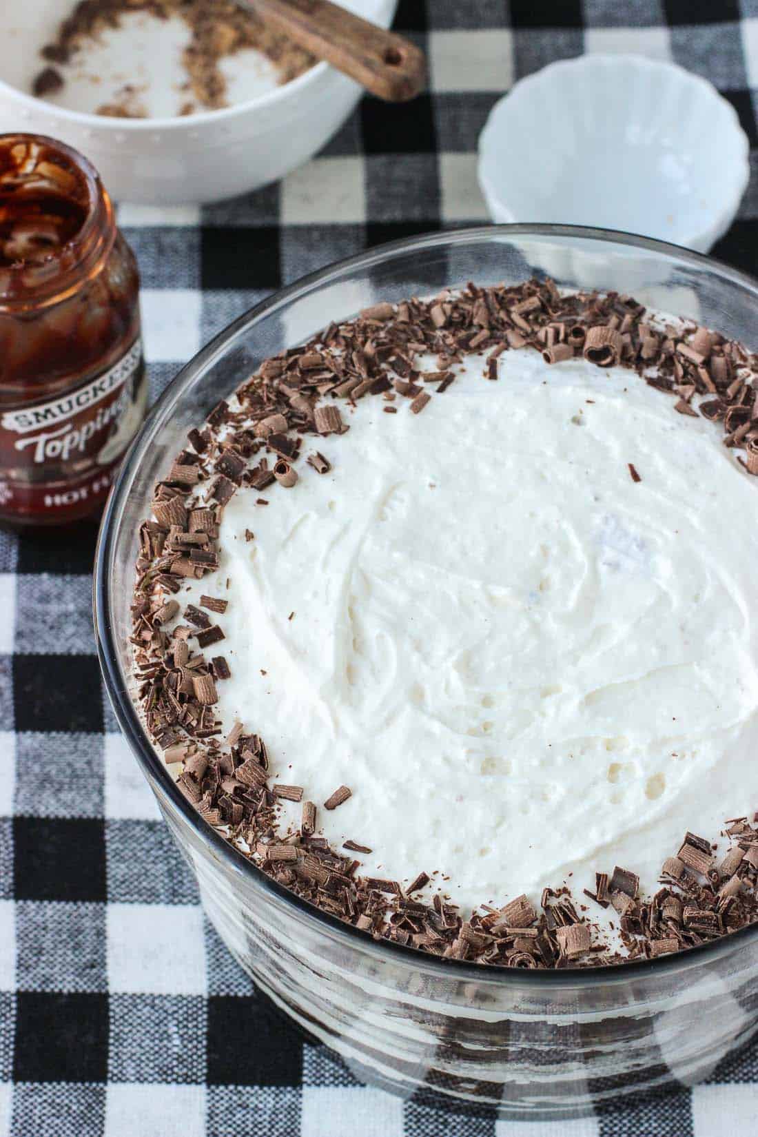 Trifle in a bowl next to a jar of fudge topping.