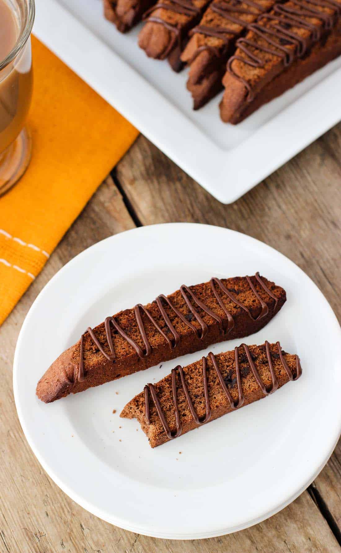 Two biscotto in a dessert plate in front of the tray of them.